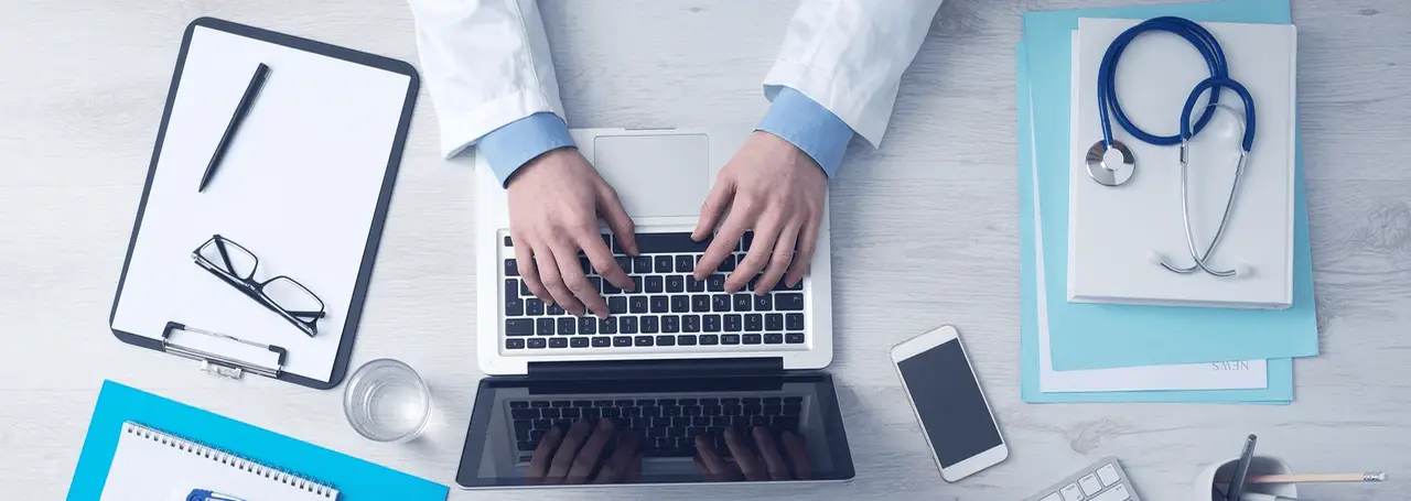 Doctor's hands typing on laptop. Photo.