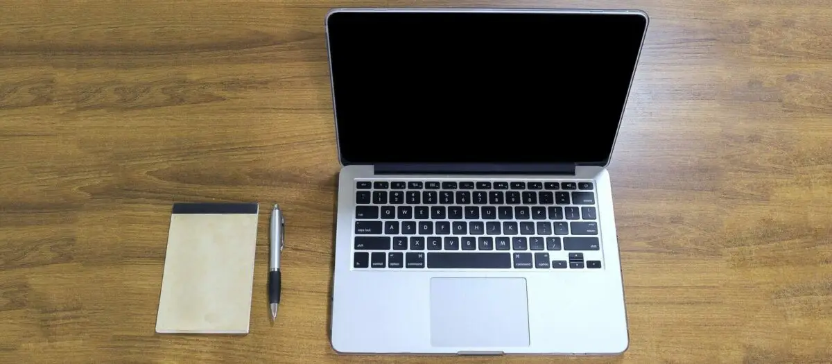 Laptop with notepad and pen beside it. Photo.