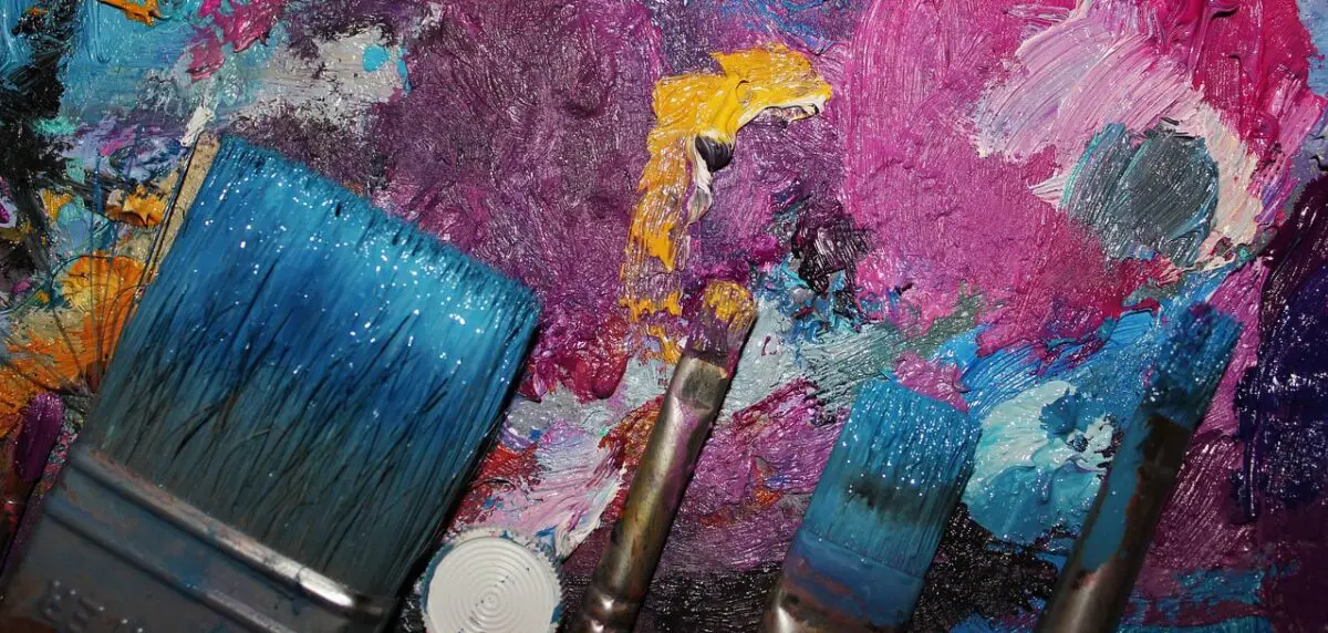 Paintbrushes with pink, blue and orange paint. Photo.