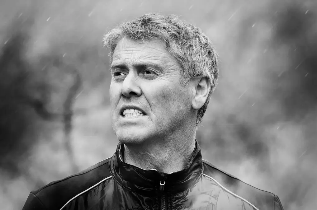 Middle aged man looking strained in the rain. Greyscale photograph with background out of focus.