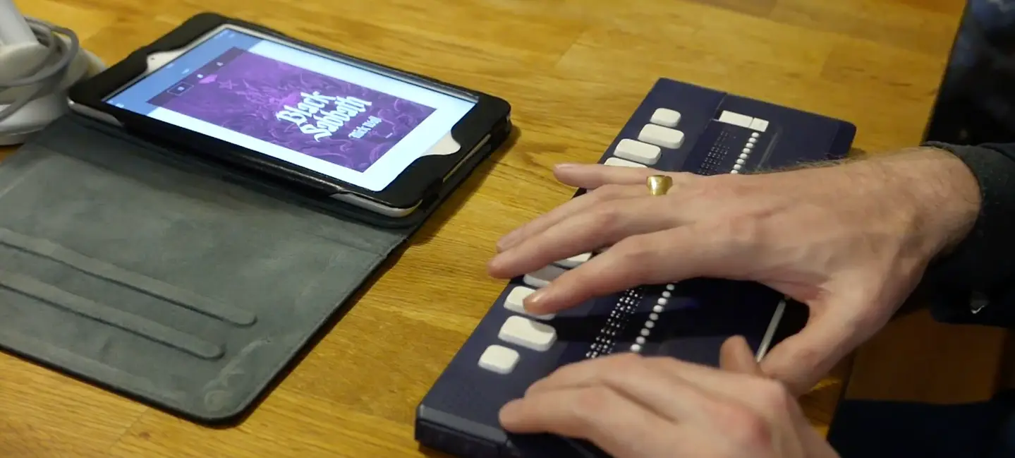 User reading from a braille display placed below his iPad. 