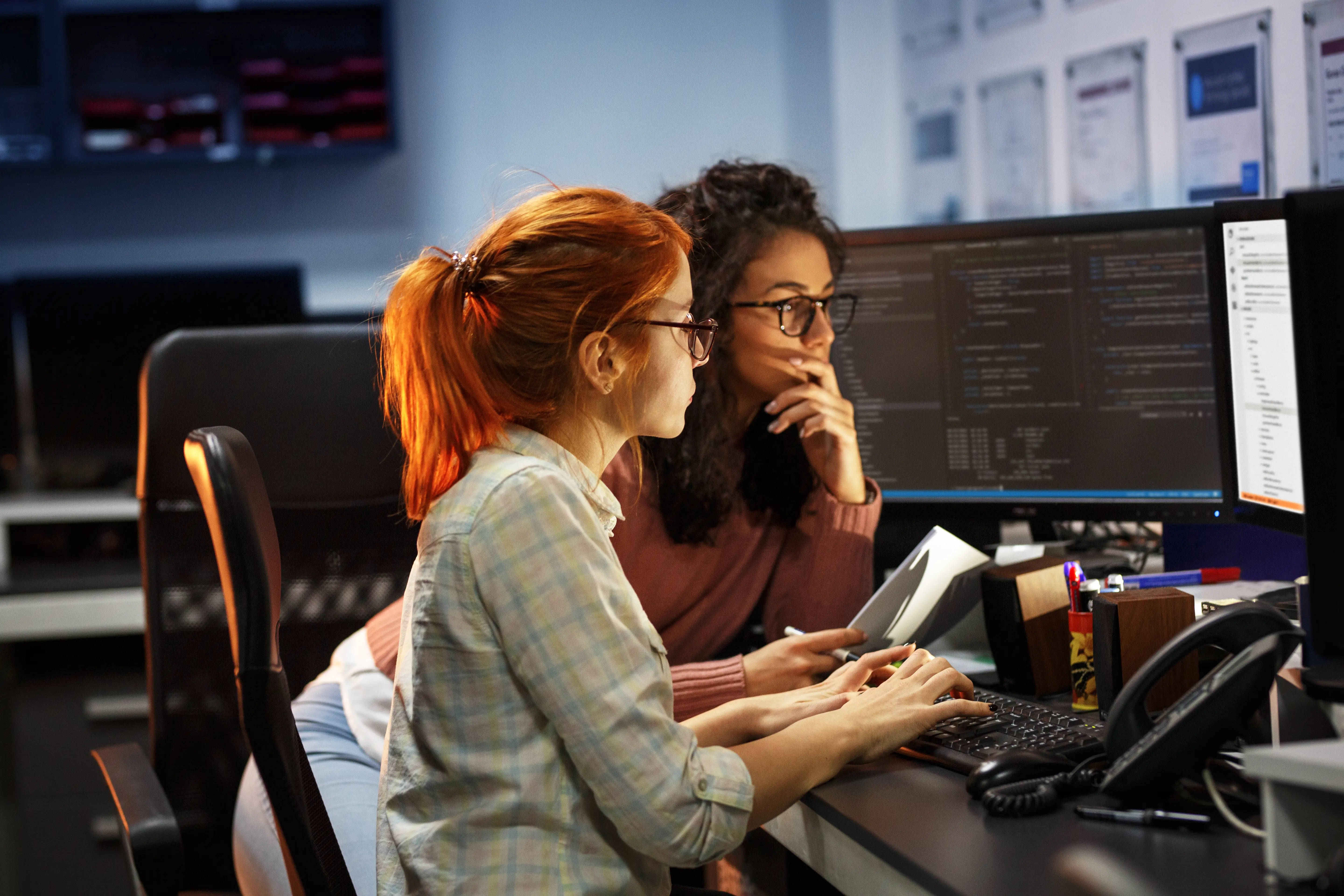 Two female developers pair programming front of a screen.