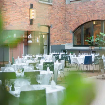 Large dining area, brick walls, white table cloth on tables