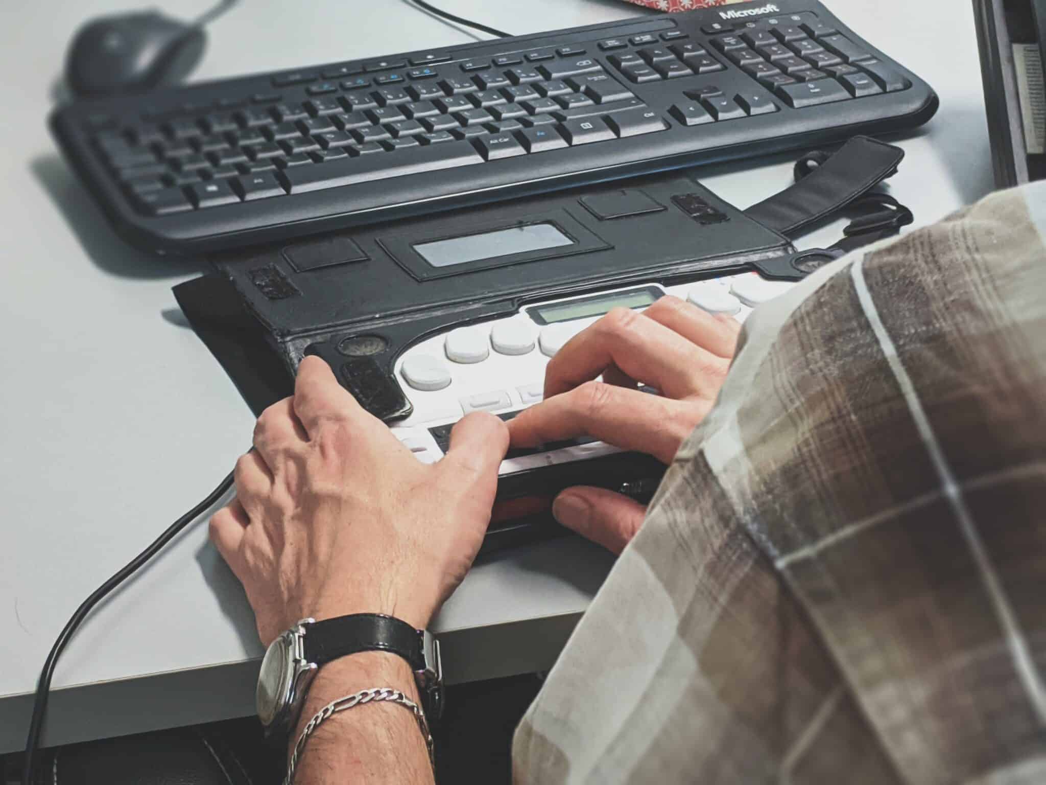 Finger, die eine Braille-Tastatur lesen