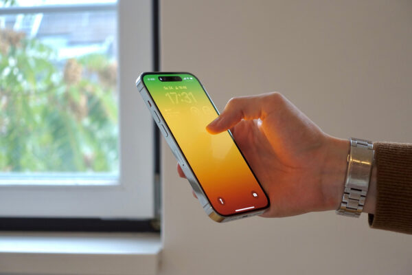 A hand holding an iPhone showing the lock screen with a colorful gradient background.