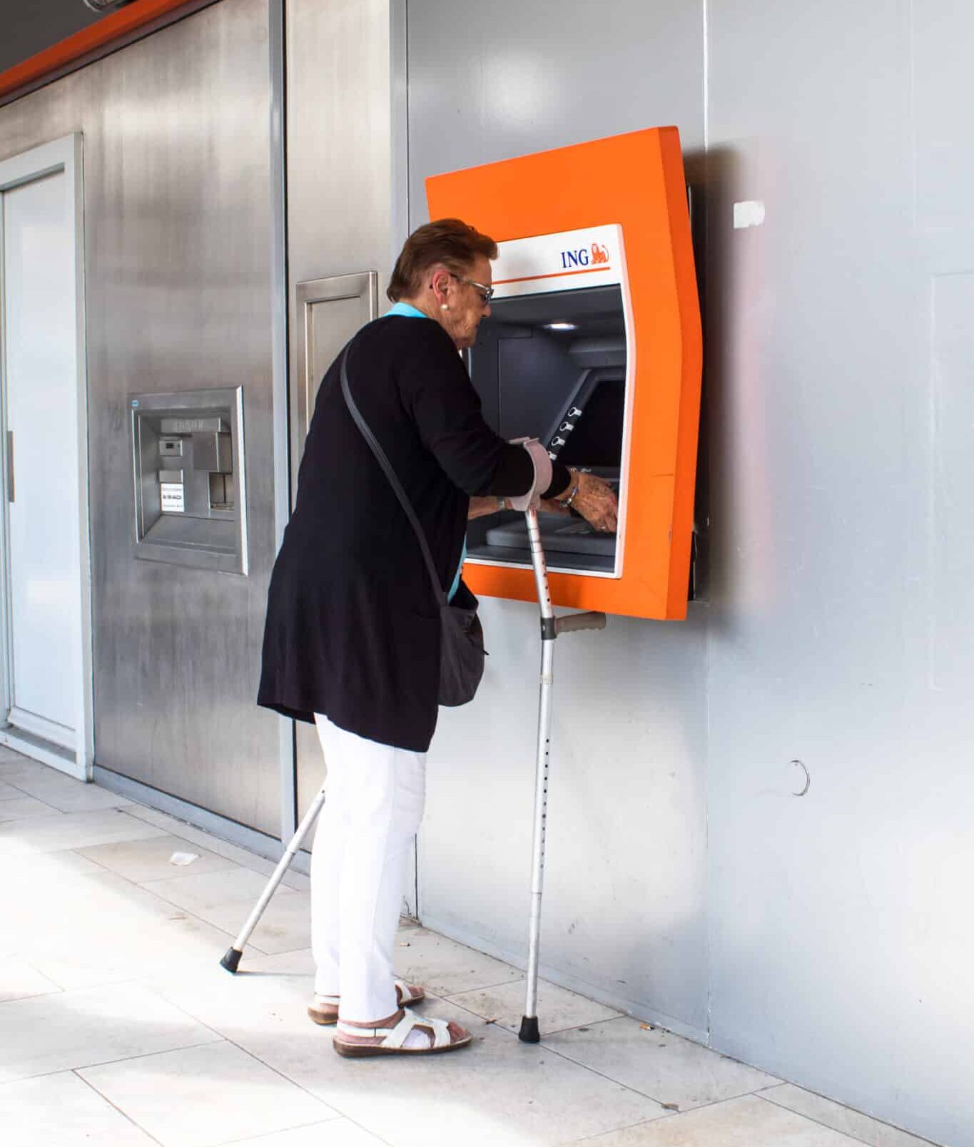 ATM being used by elderly citizen with walking aids.